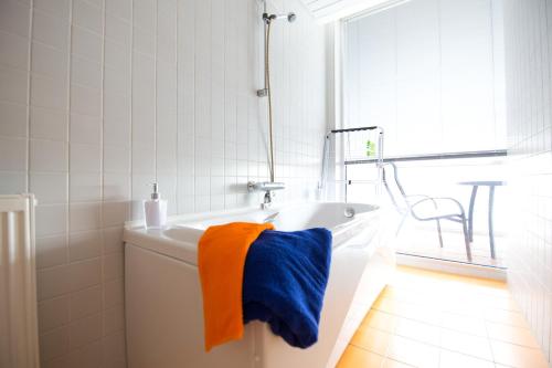 a white bath tub with an orange and blue towel at City center apartment Aida in Pärnu