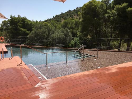 a swimming pool with a fence and a wooden deck at Jardines de La Santa in Totana