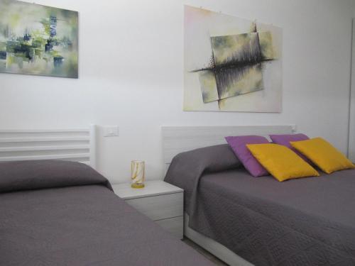 two beds in a bedroom with paintings on the wall at Station Home in Sesto San Giovanni