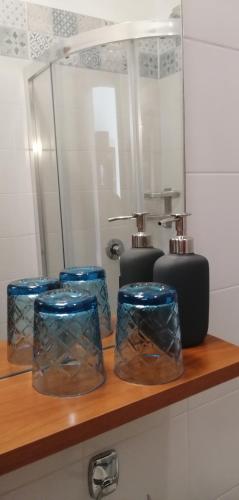 a shelf with four blue containers on it with a mirror at Villa Magnolia BB, Lago Maggiore (Massino Visconti, Italy) in Massino Visconti