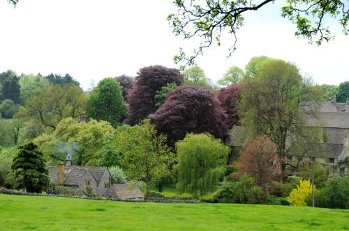a garden with trees and a house in the background at Lupin Glamping Pod in Cheltenham