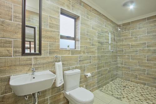 łazienka z toaletą, umywalką i oknem w obiekcie Gecko Inn w mieście Richards Bay