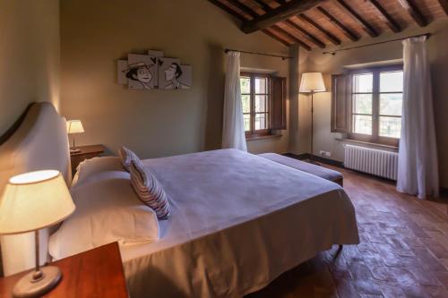 a bedroom with a large bed and two windows at Borgo dé Brandi in Monteriggioni