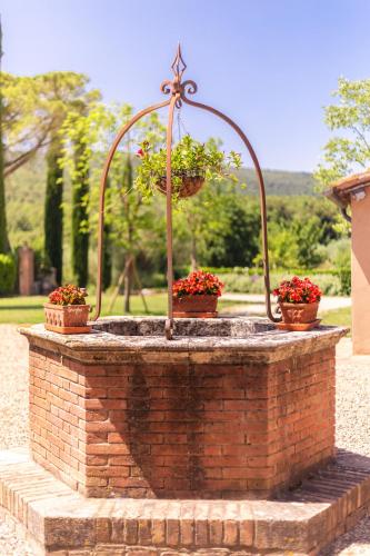 a brick fountain with three potted plants on it at Borgo dé Brandi in Monteriggioni