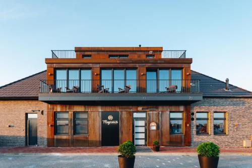 a building with a balcony on top of it at Fliegerdeich Hotel & Restaurant in Wilhelmshaven