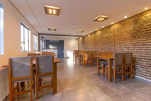 a restaurant with wooden tables and chairs and a brick wall at Hotel Viva Vida in São Borja