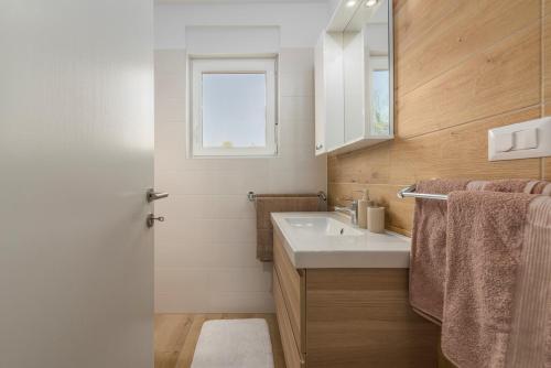 baño con lavabo blanco y ventana en Apartment Complex Jelena, en Funtana