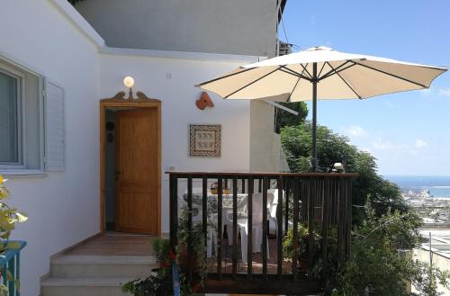 een huis met een balkon met een paraplu bij The Potter's House overlooking the Bay of Haifa in Haifa