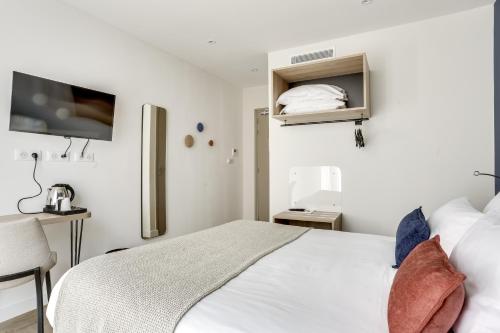 a white bedroom with a bed and a tv at Hotel Courseine in Courbevoie