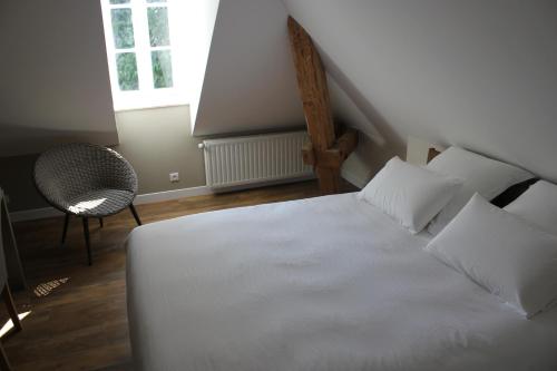 a bedroom with a white bed with a chair and a window at CLOS MARIE in Iguerande