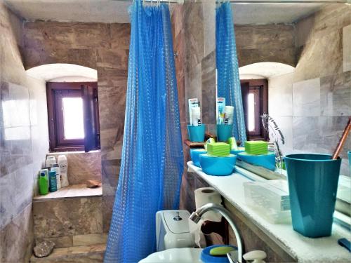 a bathroom with a blue shower curtain and a sink at Blue Horizon in Hydra