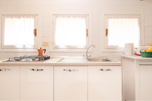 a kitchen with white cabinets and a sink and two windows at Residence Studio Vita in Bologna