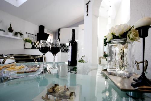 a glass table with two glasses of wine and flowers at Modern Apartment in Primošten in Primošten