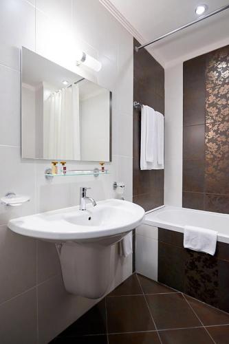 a white bathroom with a sink and a tub at Penelopa Palace Apart Hotel & SPA in Pomorie