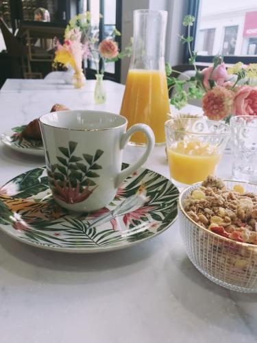 a table with a coffee cup and a bowl of food at Hôtel Cosmopolitain in Biarritz