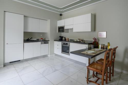 a kitchen with white cabinets and a table and chairs at Hydras Chromata in Hydra