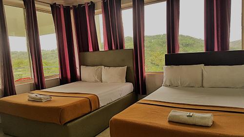 two beds in a hotel room with windows at Vagamon Clouds in Vagamon