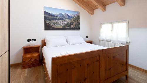 um quarto com uma grande cama de madeira com lençóis brancos em Italianway - Fiera 11 em Bormio