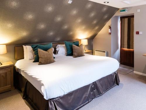 a bedroom with a large white bed with blue pillows at Craigatin House & Courtyard in Pitlochry