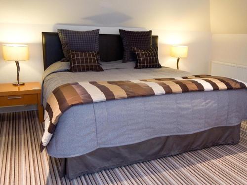 a large bed in a room with two lamps at Craigatin House & Courtyard in Pitlochry