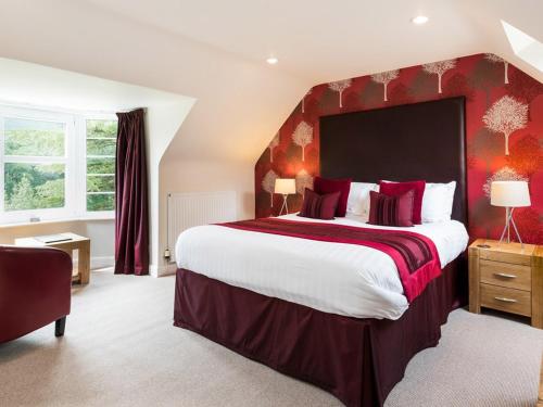 a large bedroom with a large bed with red walls at Craigatin House & Courtyard in Pitlochry