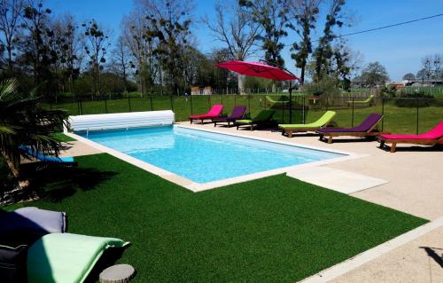 - une piscine avec des chaises et un parasol rouge dans l'établissement Domaine de la Besnerie Gites avec SPA Privatif à 10 min du Mont St Michel, à Tanis