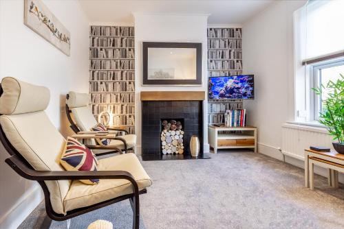 a living room with two chairs and a fireplace at Guest Homes - Farningham Residence in Caterham