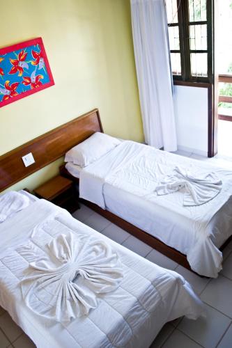 Dos camas en una habitación de hotel con sábanas blancas. en Jerusalém II - Rede Tonziro, en Mutari