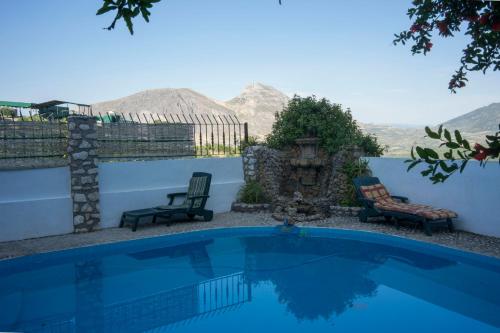 une piscine bleue avec deux chaises et des montagnes en arrière-plan dans l'établissement Hostal Caseria San José de Hutar, à Hútar