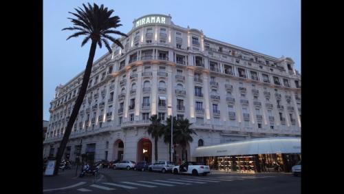un grand bâtiment blanc avec des voitures garées devant dans l'établissement 124 MIRAMAR 65 LA CROISETTE, à Cannes