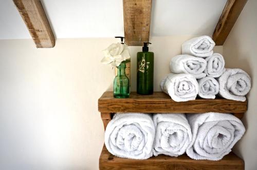 a stack of towels on a wooden shelf in a bathroom at Hopeend Holidays Cottage in Great Malvern