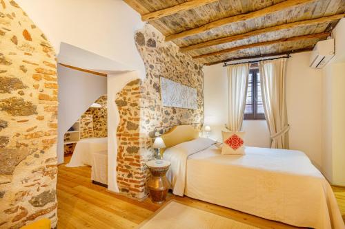 a bedroom with two beds and a stone wall at Albergo Diffuso Mannois in Orosei