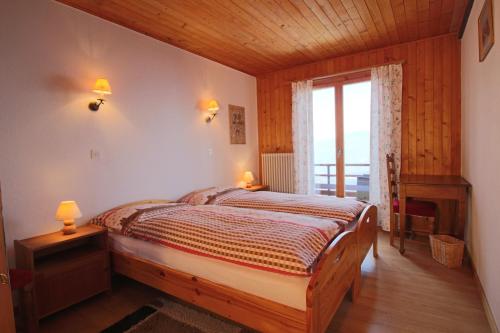 a bedroom with a bed in a room with a window at Pension Les Audannes in Anzère