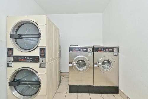two washing machines and a dryer in a room at Ramada by Wyndham Kent Seattle Area in Kent