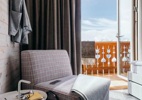 une chaise et une table dans une chambre avec balcon dans l'établissement Langley Hôtel Le Petit Prince, à L'Alpe-d'Huez