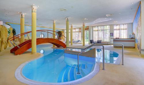 a large swimming pool with a slide in a building at Michel Hotel Magdeburg in Magdeburg