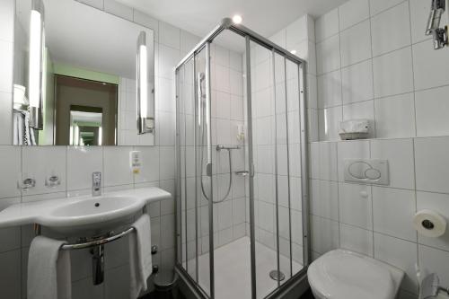 a bathroom with a shower, sink, and toilet at Hotel & Restaurant STERNEN MURI bei Bern in Bern