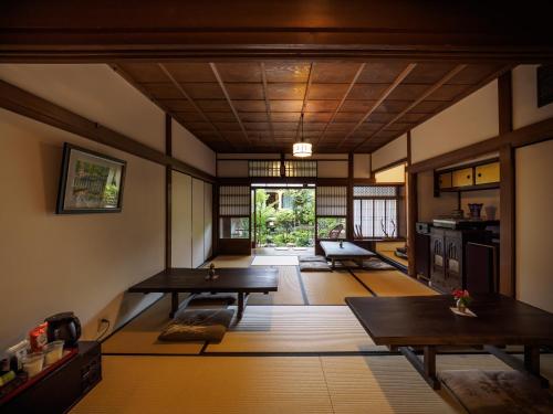 ein Wohnzimmer mit Holztischen und eine Küche in der Unterkunft Inase Otsu Machiya Bed and Breakfast in Ōtsu