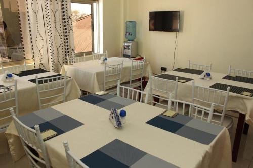 a room with several tables and chairs and a tv at Gees Inn in Nakuru