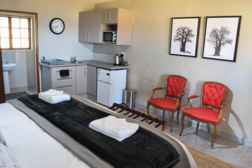 a kitchen with two red chairs and a table at Merino Guest Farm in Clarens