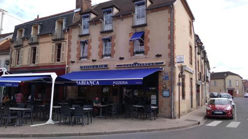 a building with tables and chairs on a city street at Hôtel Casabianca in Moulins