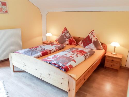 - une chambre avec un grand lit en bois et des oreillers rouges dans l'établissement FeWo Kreitl, à Waldmünchen