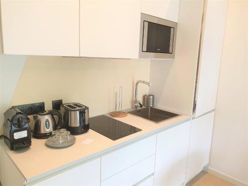 une cuisine blanche avec un évier et un micro-ondes dans l'établissement STUDIO CENTRE MER 301, à Nice
