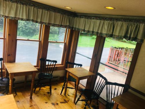 twee tafels en stoelen in een kamer met ramen bij Carriage Barn Inn in Keene