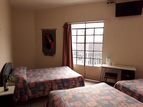 a hotel room with two beds and a window at Hotel Janeiro in Guadalajara
