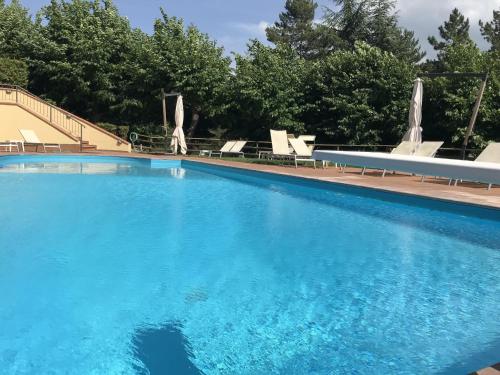 a large blue swimming pool with chairs and trees at Grand Hotel Admiral Palace in Chianciano Terme