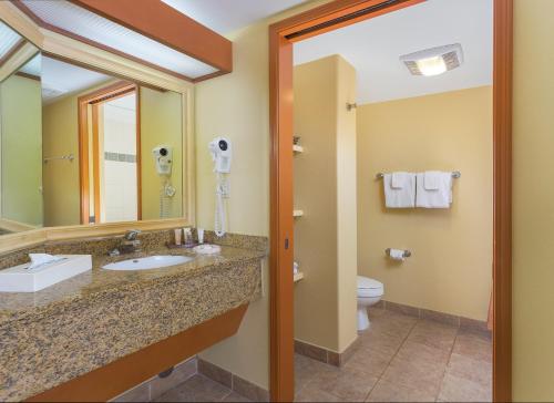 a bathroom with a sink and a toilet and a mirror at Kauai Coast Resort at the Beach Boy in Kapaa