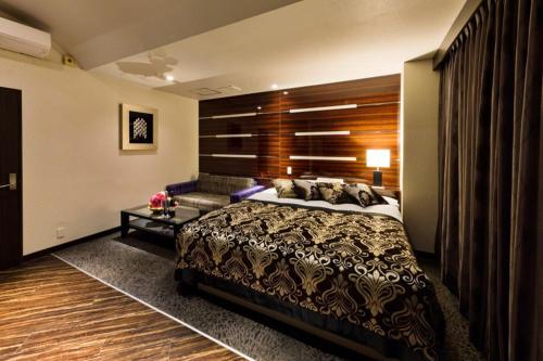 a bedroom with a large bed and a couch at HOTEL VERSYS (Adult Only) in Hiroshima