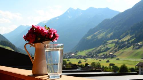 a vase with a flower and a glass of water at Fleckhof in Neustift im Stubaital