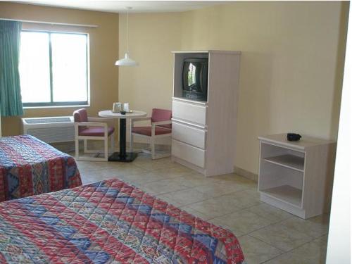 a hotel room with a bed and a tv and a table at Miami Princess Hotel in Miami